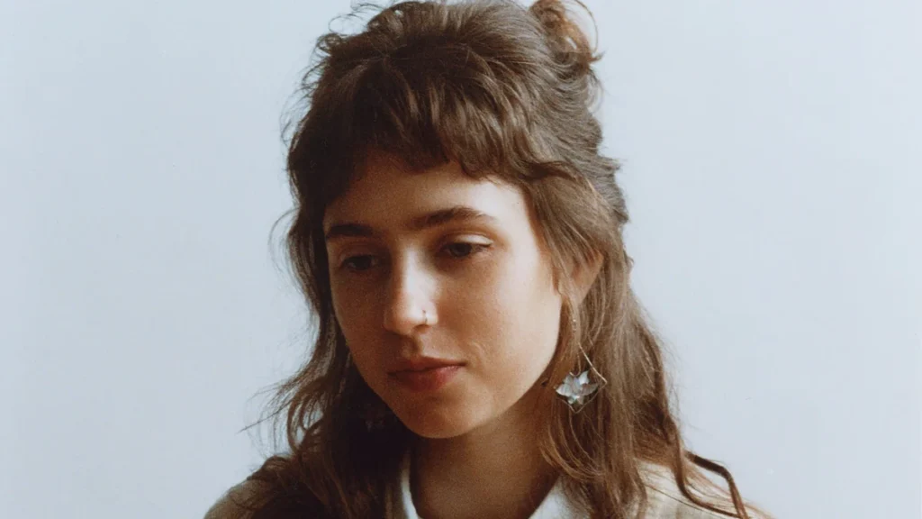 Portrait of Clairo against a pale background