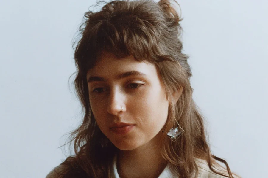 Portrait of Clairo against a pale background