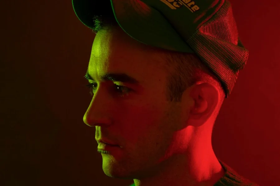 Sufjan Stevens in a trucker cap under red and green light